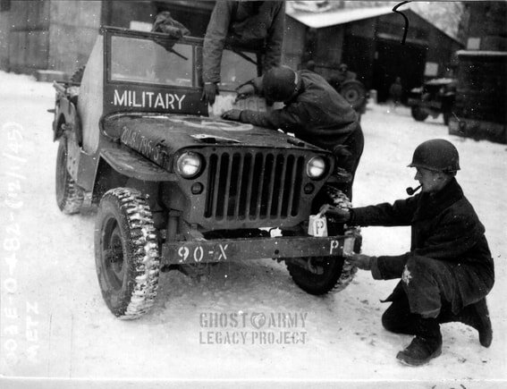 Soldiers applying markers to the windshield an bumper of a military jeep