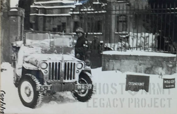Whitewashed military jeep with soldier standing to the side in the snow