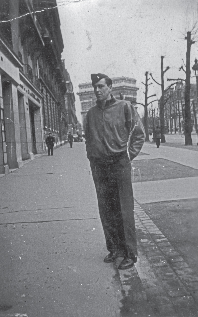 uniformed man standing on a street in Paris with the Arc de Triomphe in the background