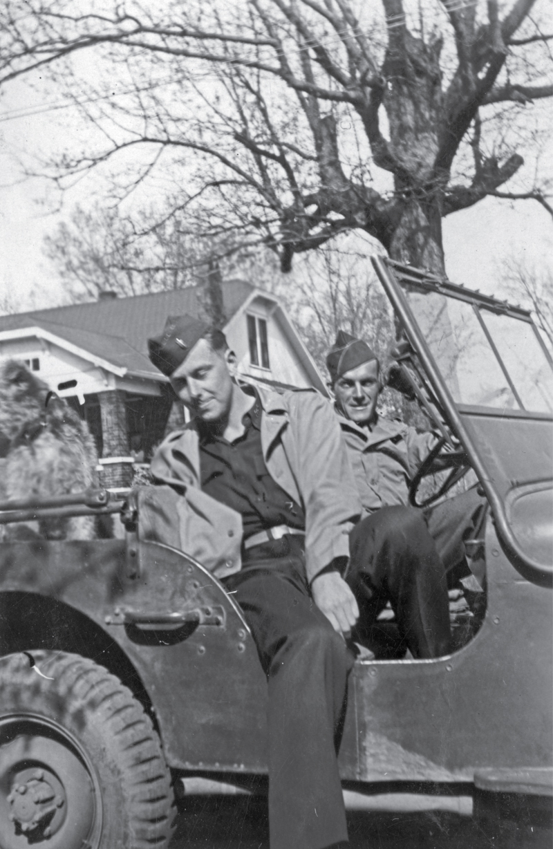 two men in uniform in a jeep outside of a home