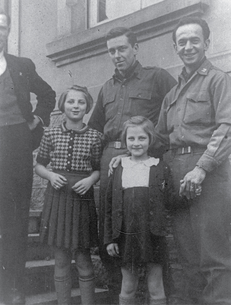 two soldiers standing with two young girls