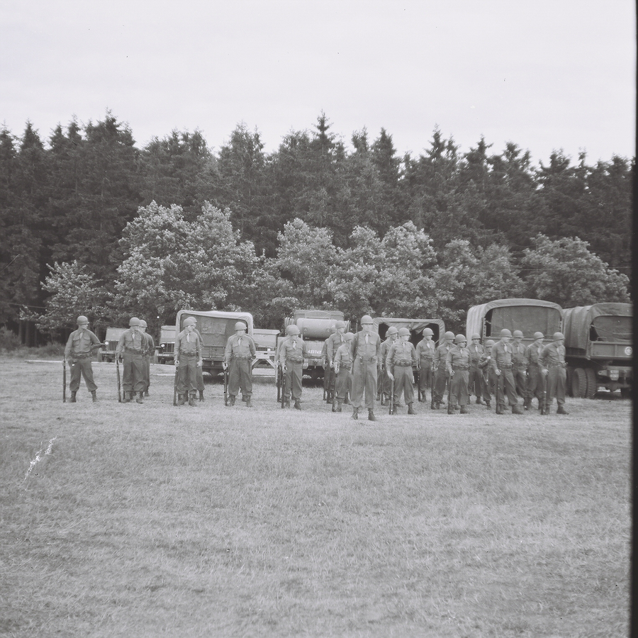 Soldiers lined up at attention in front of some trucks