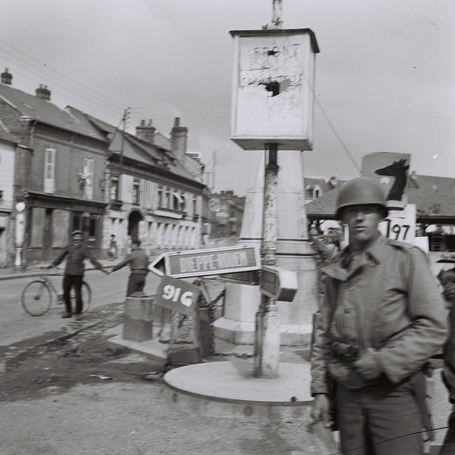 Soldier standing in front of a street sign for DieppeRouen