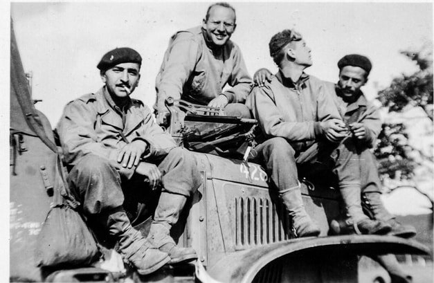 four uniformed men sitting on a jeep