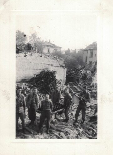 a group of men in front of a damaged building with piles of bottles on the ground
