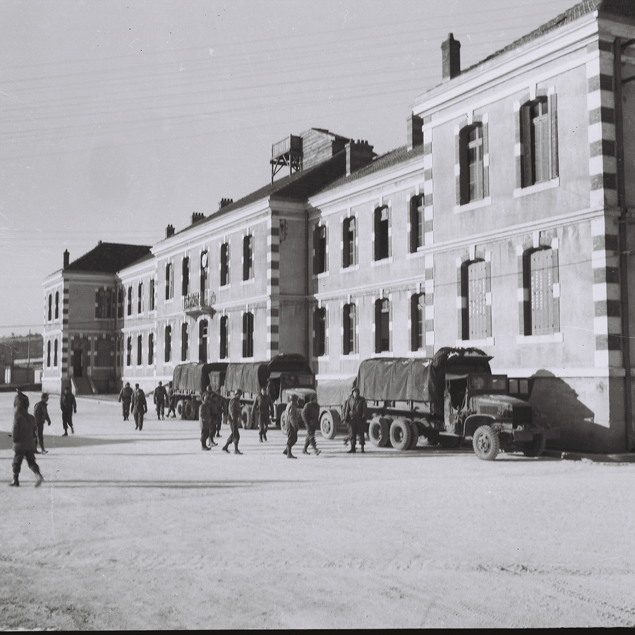 Trucks and soldiers in front of a large building