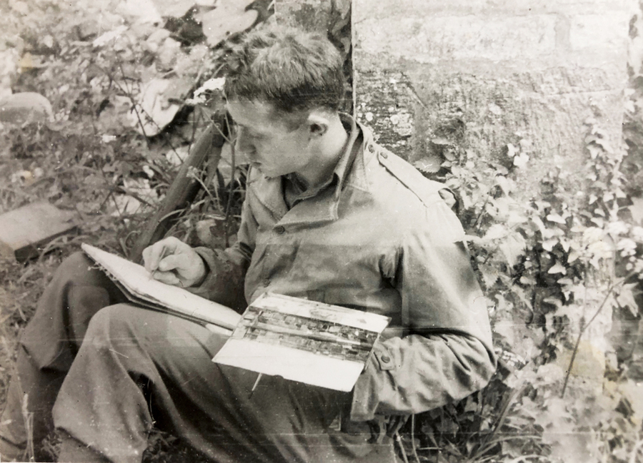 uniformed man seated, leaning against a tree and working on a watercolor painting