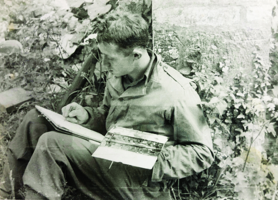 uniformed man seated, leaning against a tree and working on a watercolor painting
