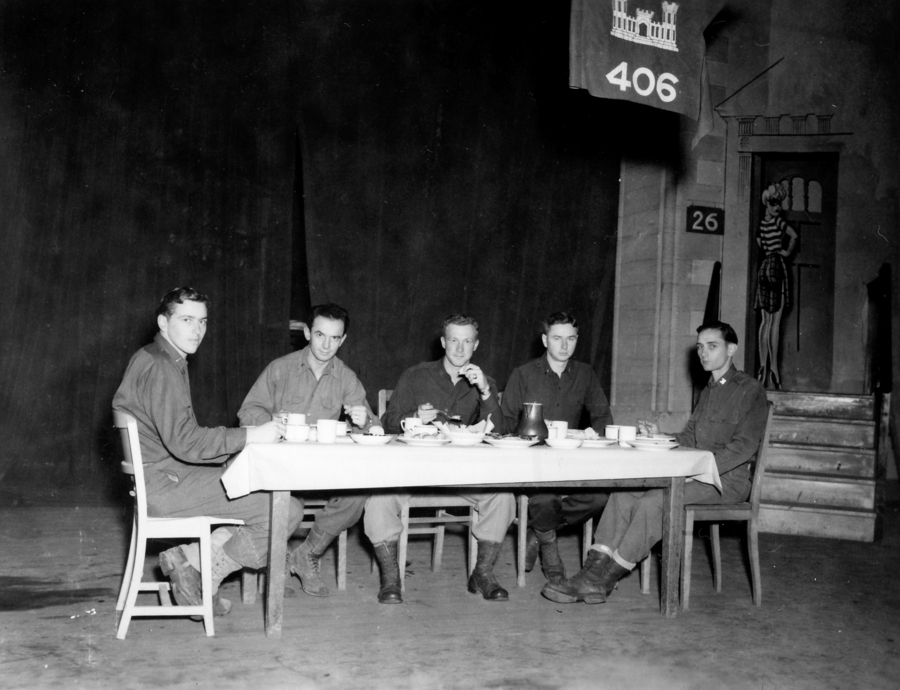 Five men at a table eating under a 406 sign