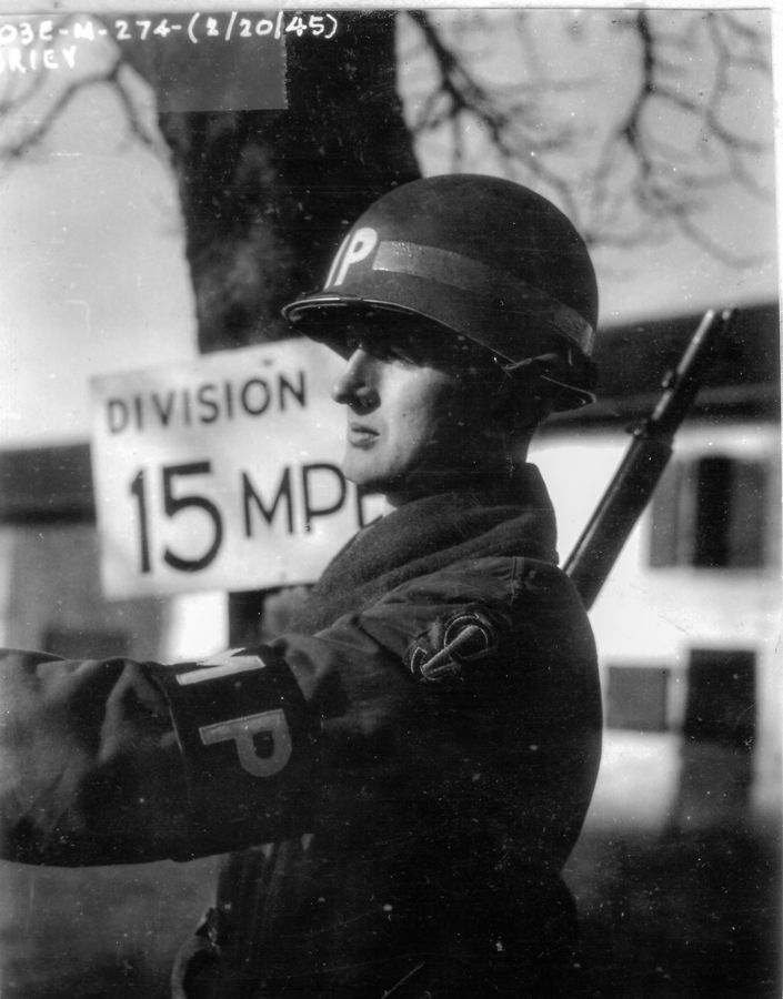 Soldier with gun standing next to a sign