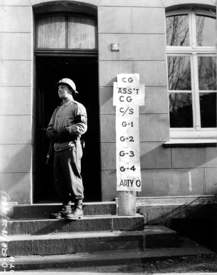 Soldier standing near a sign outside of a building