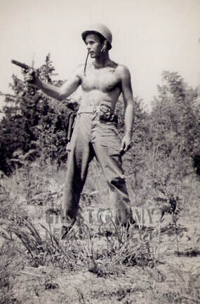 shirtless soldier posing in field with handgun