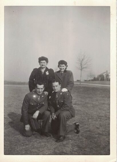two soldiers posing in a field with two women in ww2