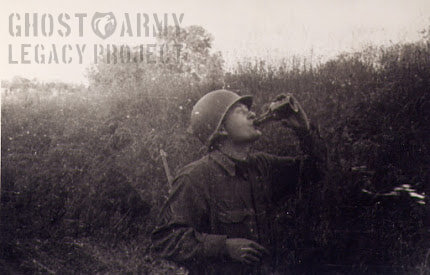 helmeted soldier in world war 2 drinking from a bottle