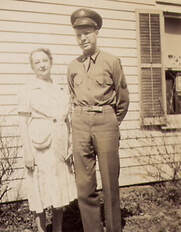 uniformed soldier standing outside a house with an older woman