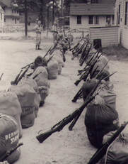 soldier packs and rifles in rows on the ground
