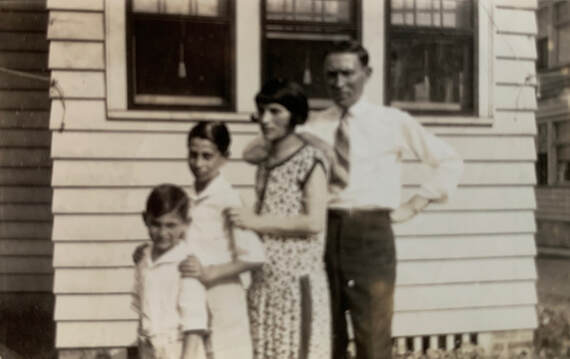 two boys, a woman and a man standing in front of a house in height order