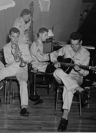 four men in uniform, seated and playing instruments