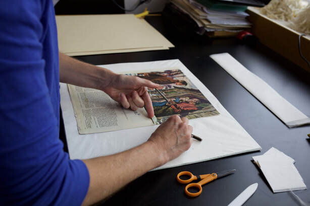 woman reassembling scrapbook page for conservation