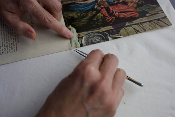 woman repairing torn image in  scrapbook page during conservation
