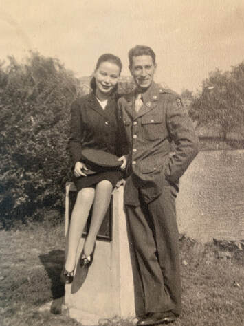 man in uniform and woman seated posing in a back yard