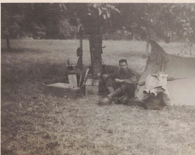 Soldier sitting outside of a tent with munitions